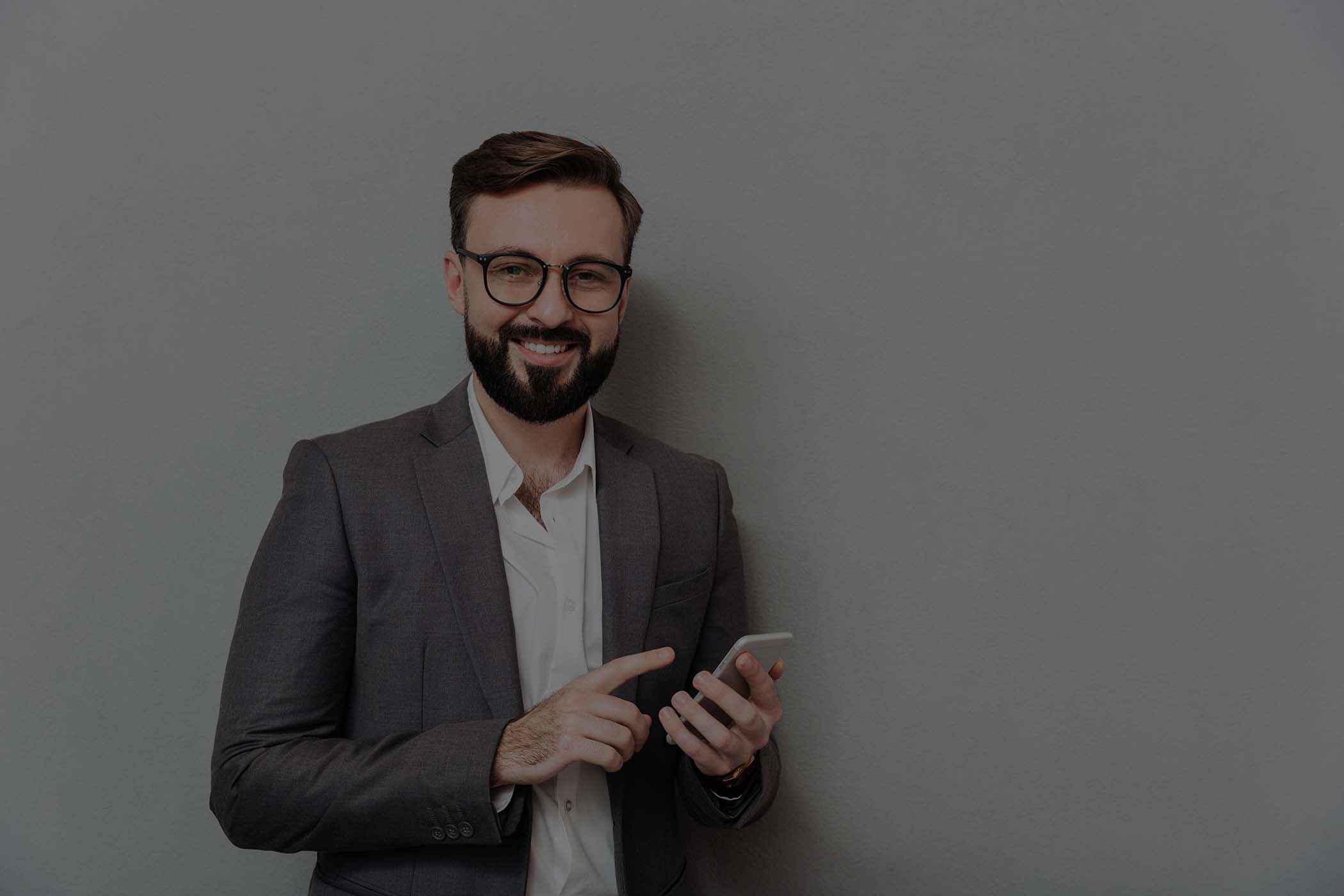 smiling man in white shirt typing text message or scrolling feed in social network using smartphone over gray overlay