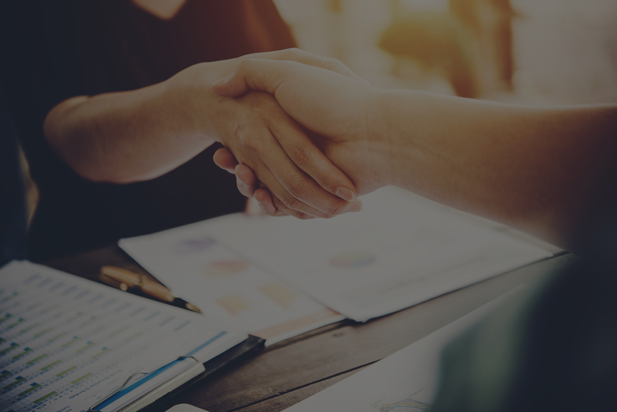 close up of two business people shaking hands while sitting at the working place low overlay