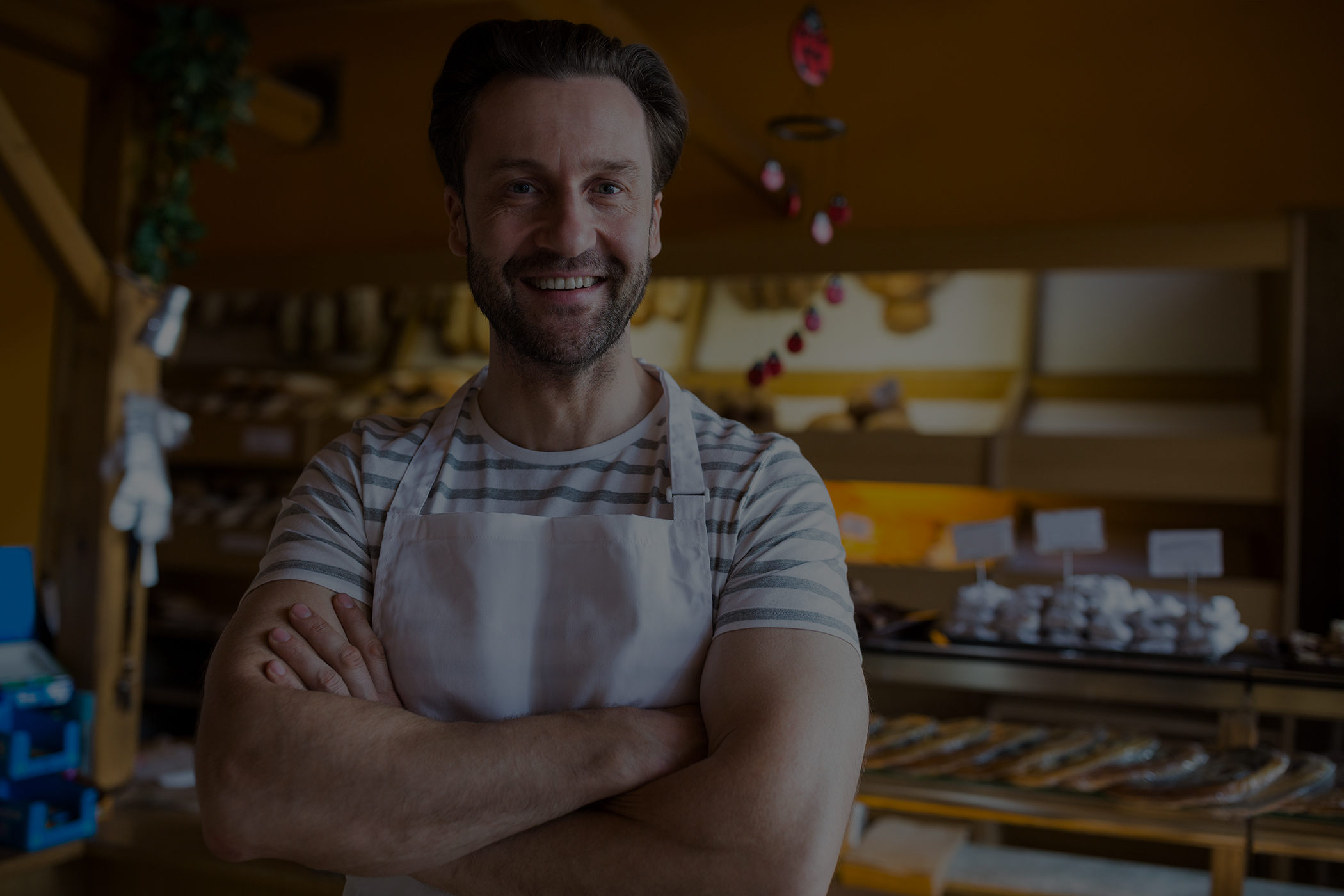 portrait of smiling owner standing in bakery shop low overlay