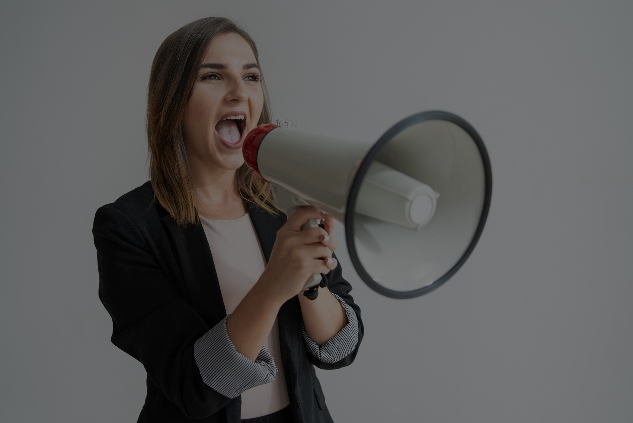 confident young caucasian woman shouting aside in megaphone low overlay